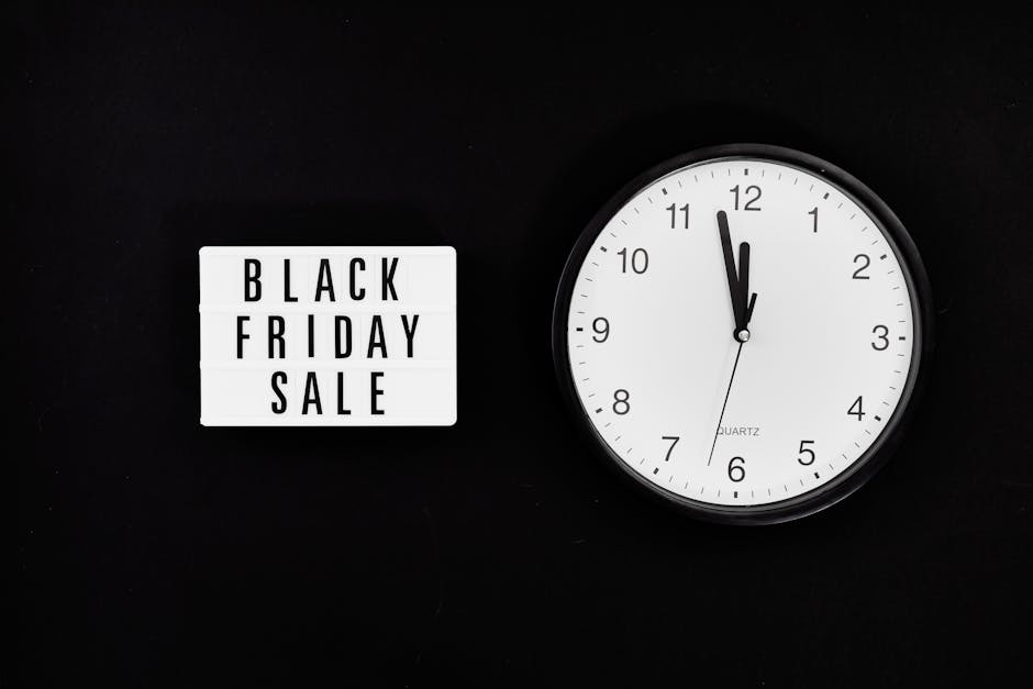 A black background features a white rectangular sign displaying bold black text that reads 'BLACK FRIDAY SALE', positioned on the left side. To the right, there is a round, white clock with black numb